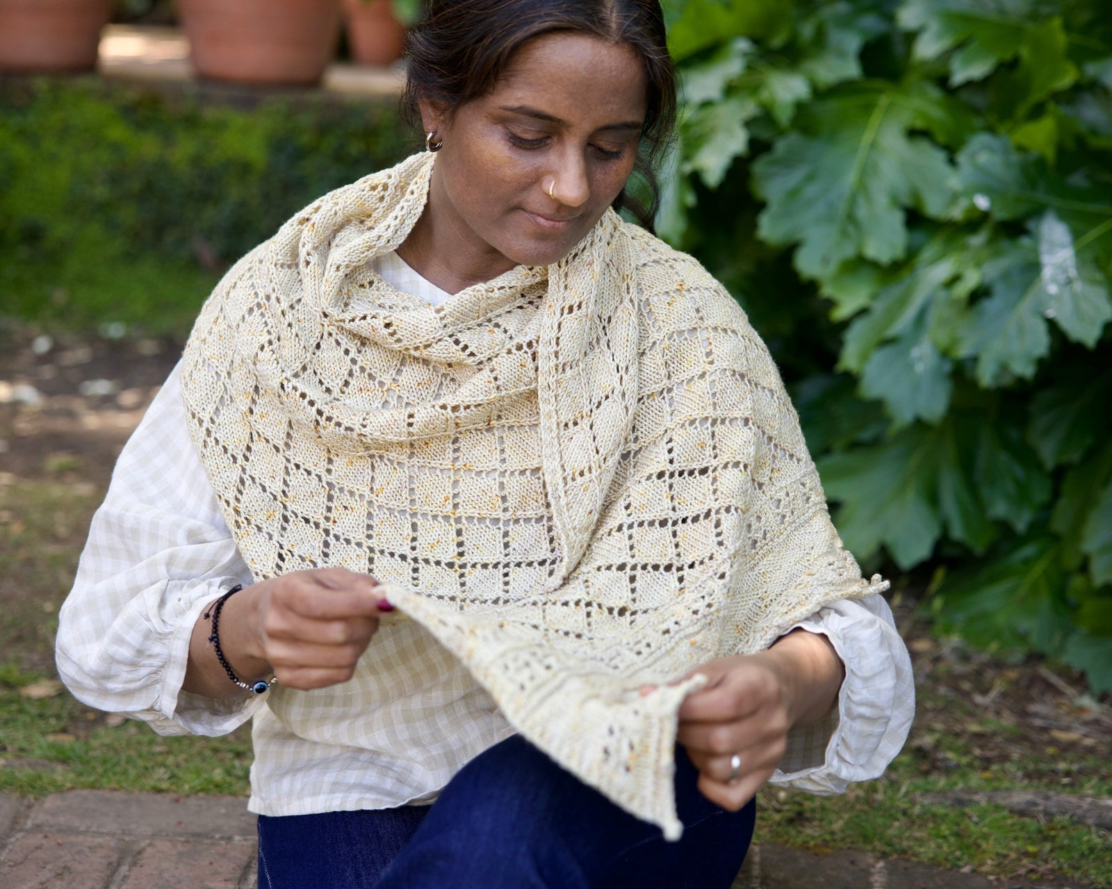 Woman wearing a cream-colored knitted shawl outdoors
