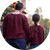 Parent and child are standing, backs to the camera. They are wearing matching deep red-colored handknit cardigans.