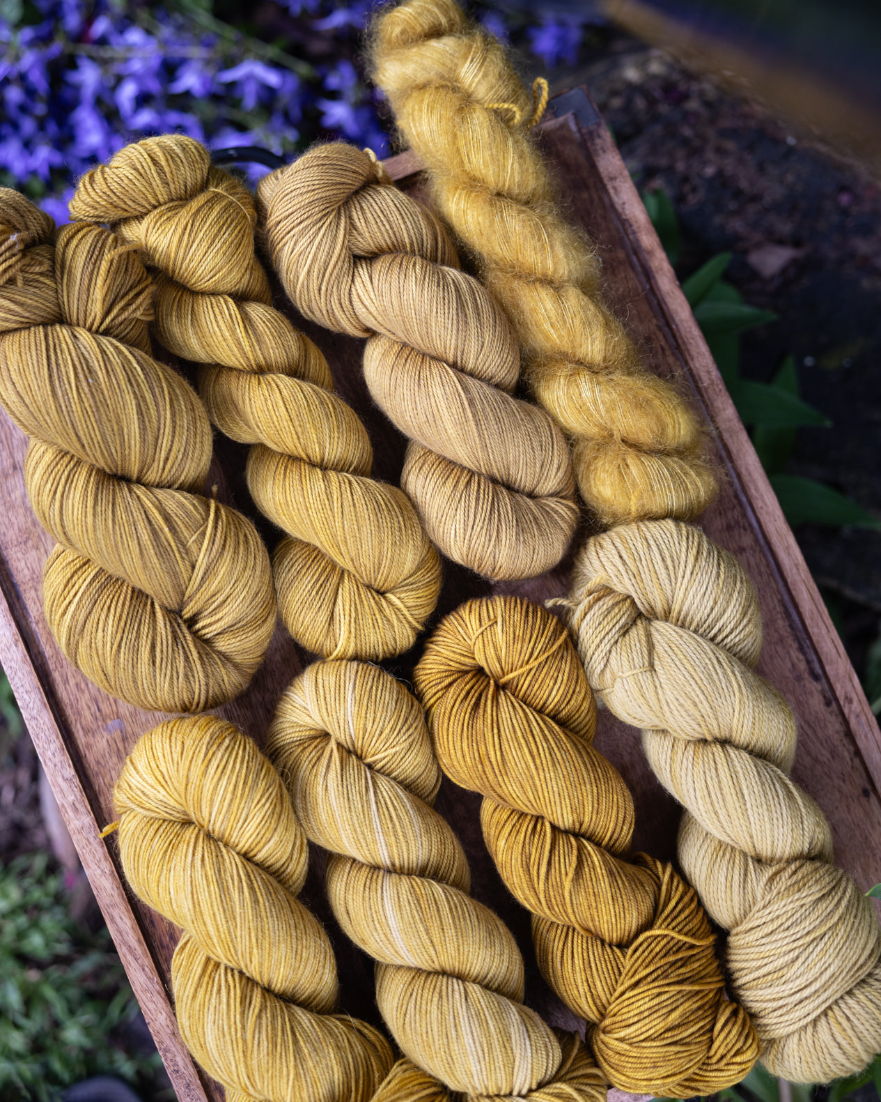 8 skeins of yarn, all dyed the same color, but on 8 different bases to show color variations