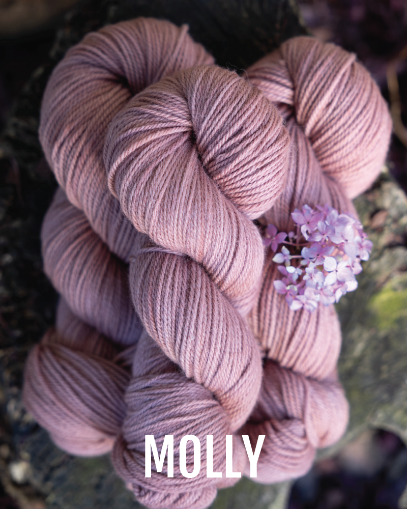 A stack of hand-dyed worsted weight  yarn in a terracotta pink